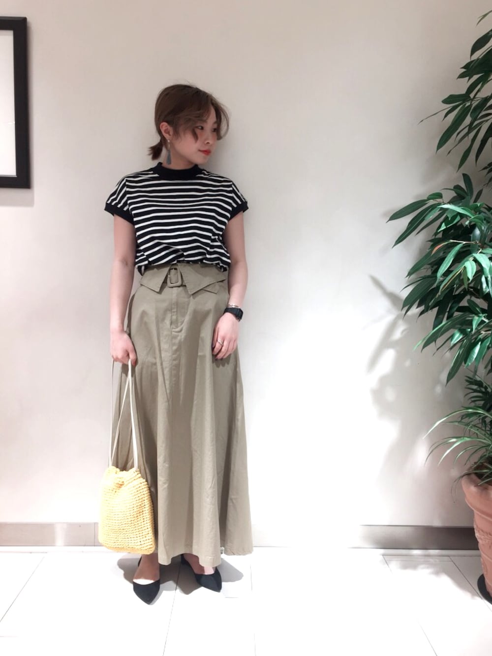 ブルー系のTシャツ/カットソー、ベージュ系のスカート、イエロー系のハンドバッグを着用したレディースの春コーディネートの1枚目の写真
