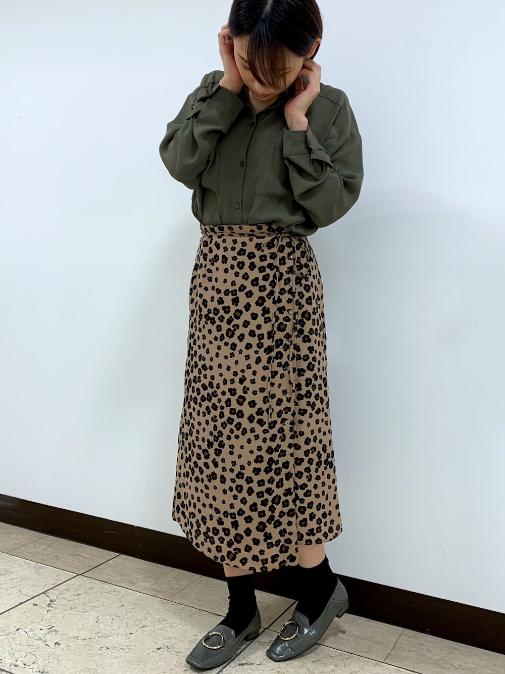 ブラウン系のスカート、グリーン系のローファー、グリーン系のトップスを着用したレディースの秋コーディネートの1枚目の写真