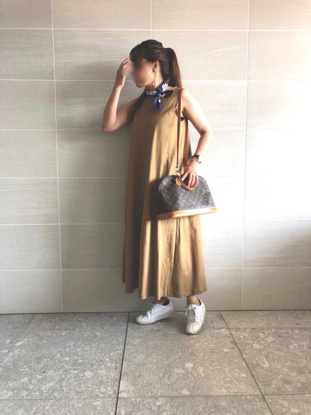 ベージュ系のワンピース、ブラウン系のボストンバッグ、ホワイト系のスニーカーを着用したレディースの秋コーディネートの1枚目の写真