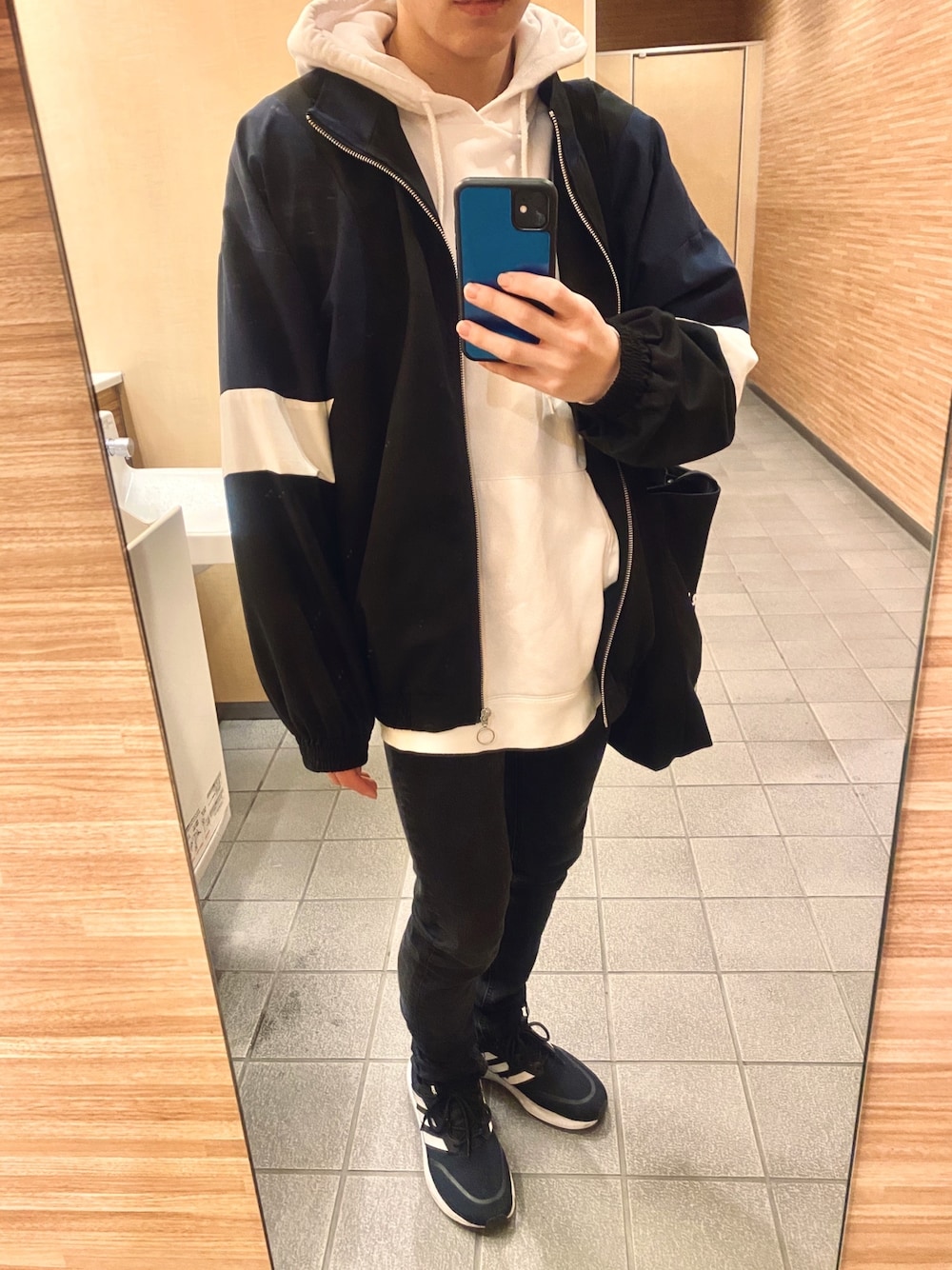 ホワイト系のパーカー、ブラック系のパンツ、ブルー系のブルゾンを着用したメンズの冬コーディネートの1枚目の写真