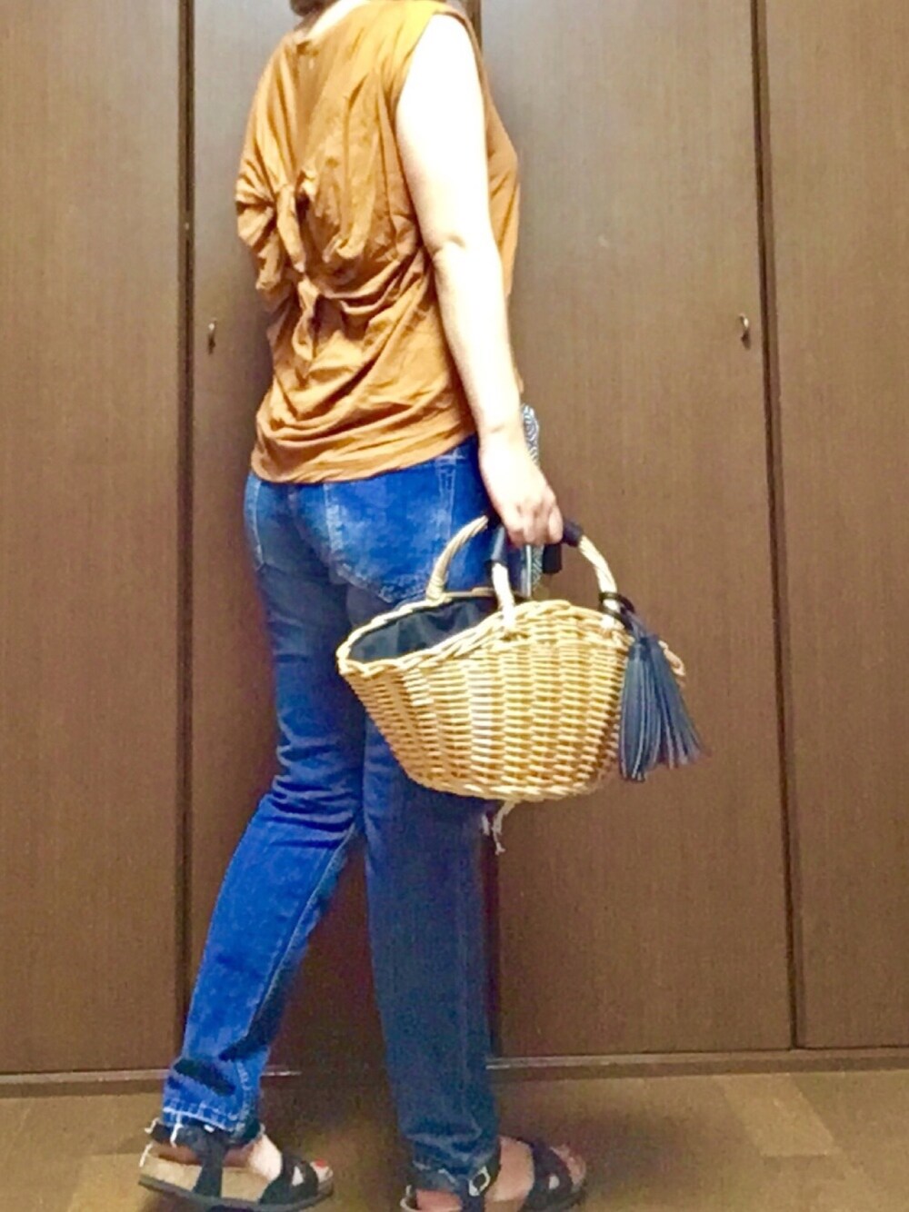 ブラック系のハンドバッグ、ブラック系のサンダル、ブラウン系のTシャツ/カットソーを着用したレディースの夏コーディネートの1枚目の写真