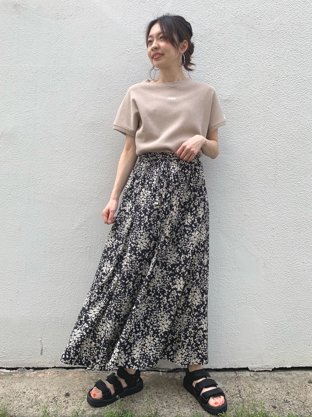ベージュ系のTシャツ/カットソー、ブラック系のスカート、ブラック系のサンダルを着用したレディースの春コーディネートの1枚目の写真