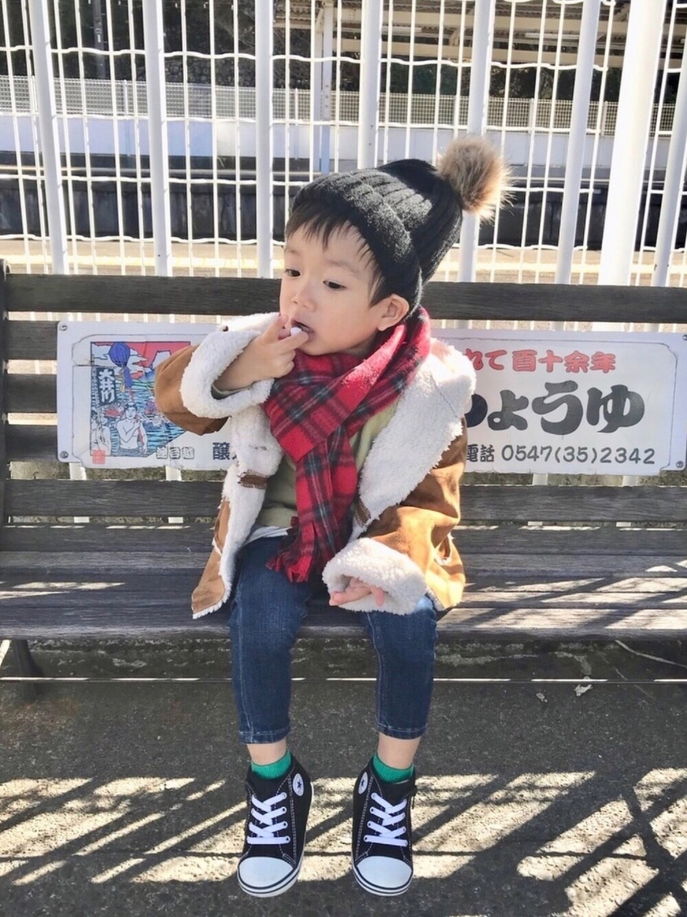 ブラウン系のムートンコート、グリーン系のTシャツ/カットソー、ブルー系のデニムパンツを着用したキッズの秋コーディネートの1枚目の写真