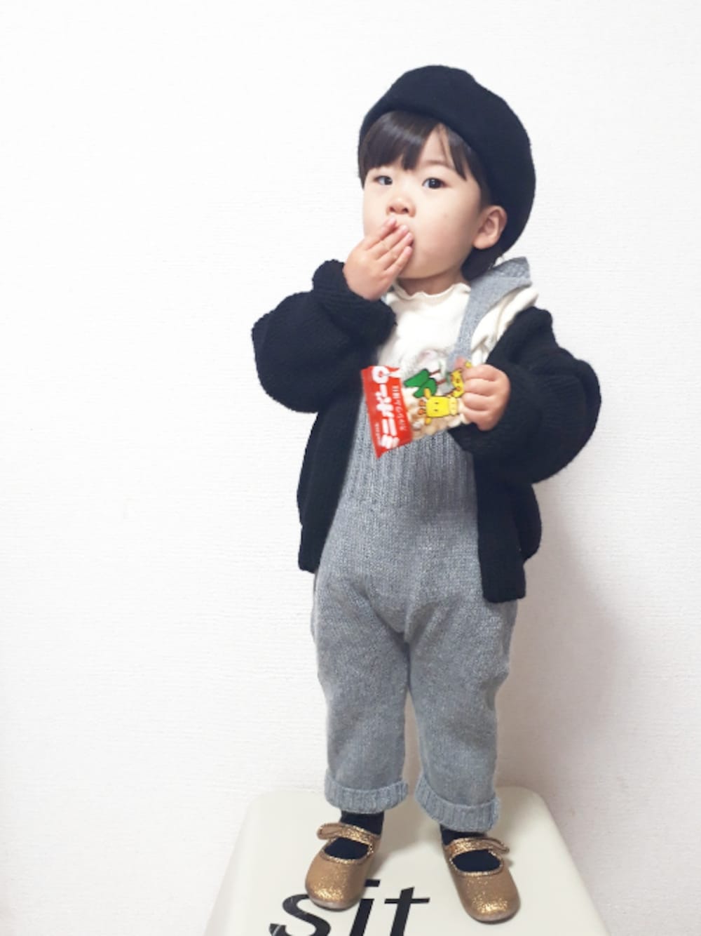 グレー系のオールインワン・サロペット、ブラック系のカーディガン/ボレロ、ベージュ系のTシャツ/カットソーを着用したキッズの冬コーディネートの1枚目の写真