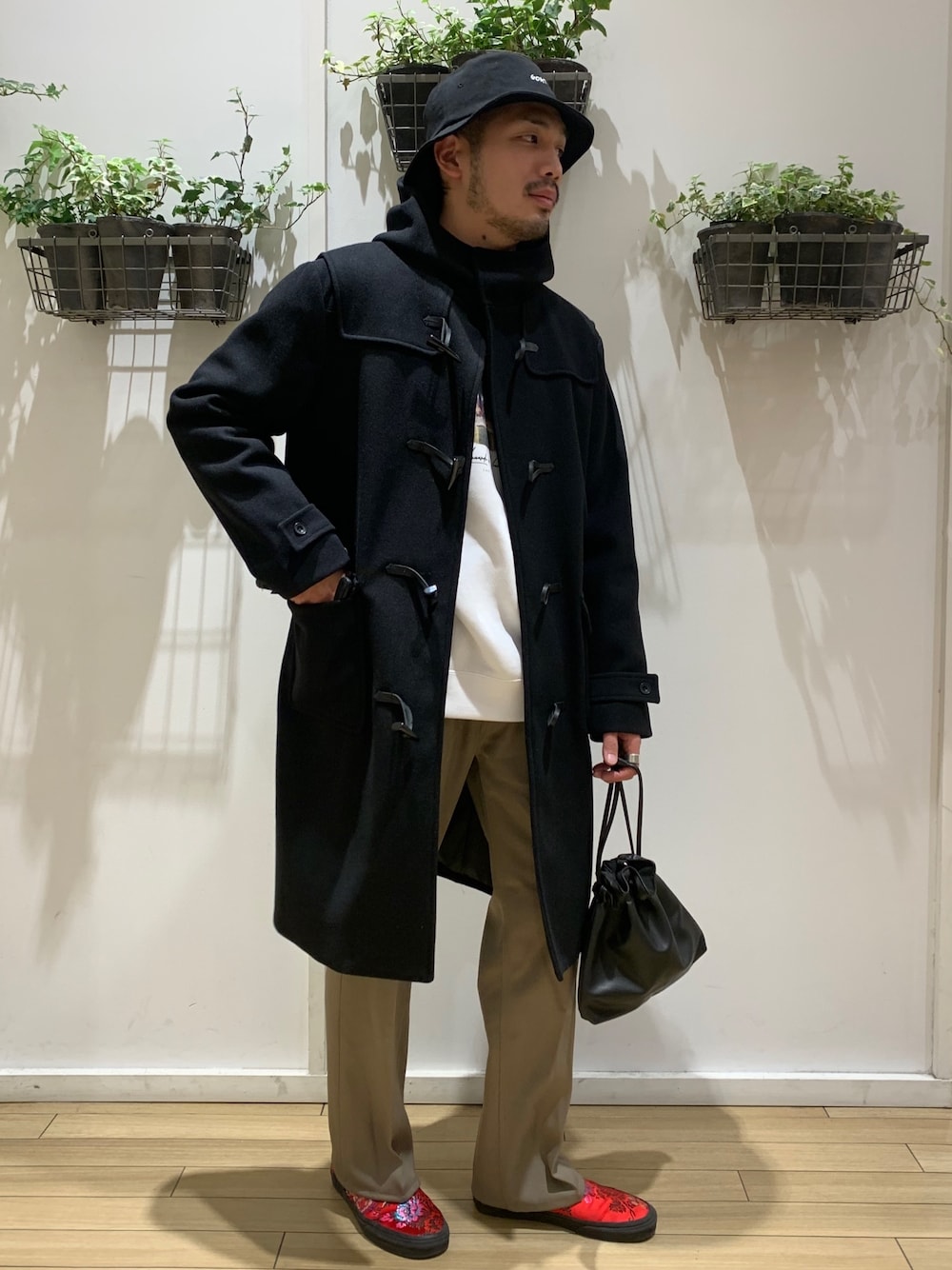 ブラック系のダッフルコート、ホワイト系のTシャツ/カットソー、ベージュ系のスラックスを着用したメンズの冬コーディネートの1枚目の写真