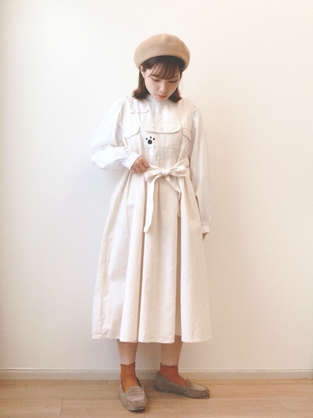 ベージュ系のジャンパースカート、ホワイト系のシャツ/ブラウス、ベージュ系のモカシン/デッキシューズを着用したレディースの秋コーディネートの1枚目の写真