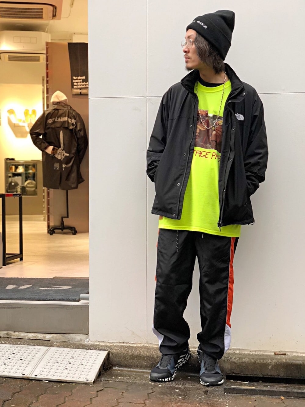 ブラック系のマウンテンパーカー、ブラック系のスニーカー、イエロー系のTシャツ/カットソーを着用したメンズの秋コーディネートの1枚目の写真