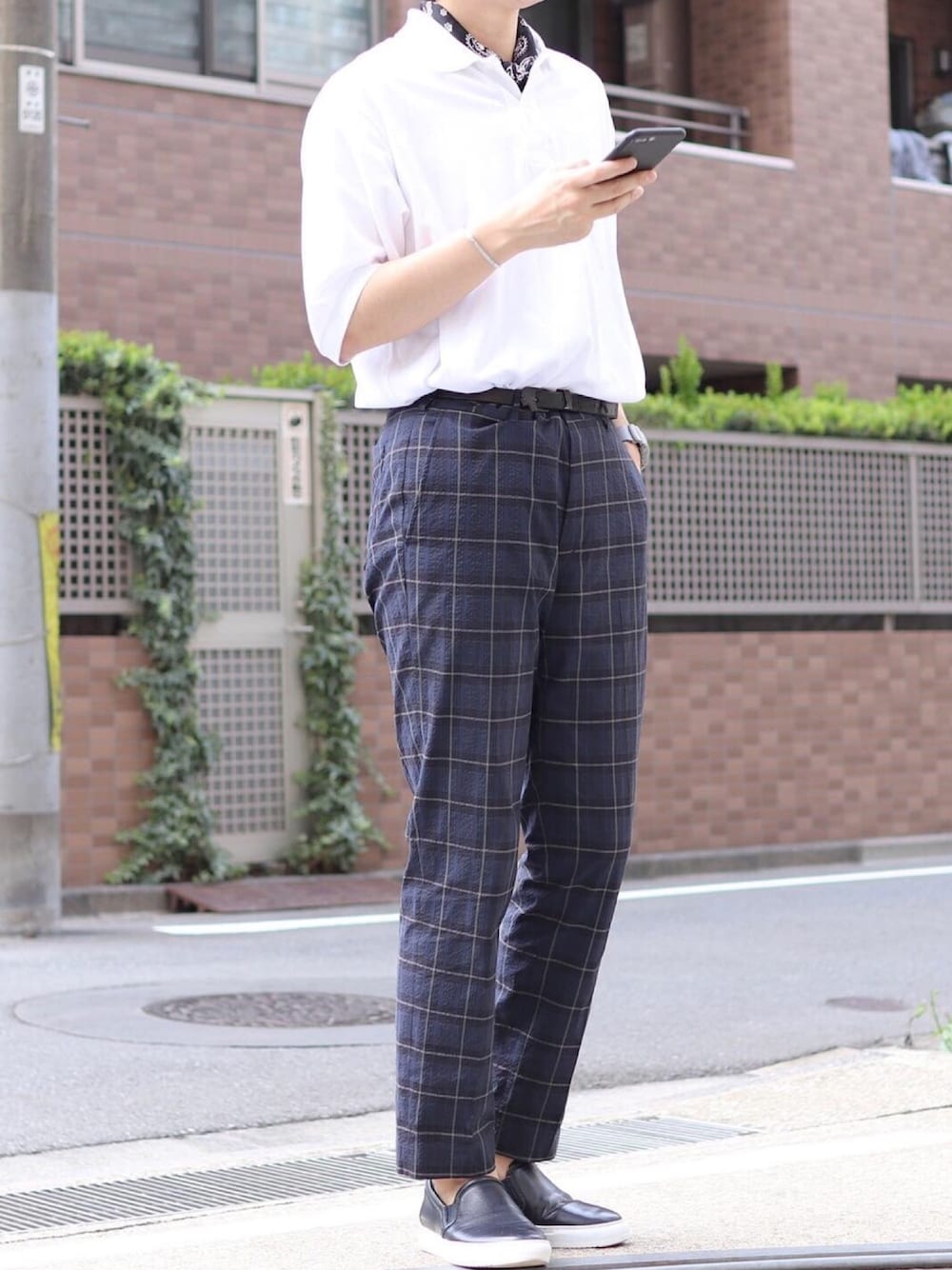 ホワイト系のポロシャツ、ブルー系のパンツ、ブラック系のスリッポンを着用したメンズの夏コーディネートの1枚目の写真