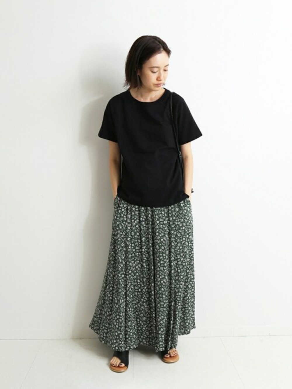 グリーン系のスカート、ブラック系のTシャツ/カットソー、ブラック系のショルダーバッグを着用したレディースの春コーディネートの1枚目の写真