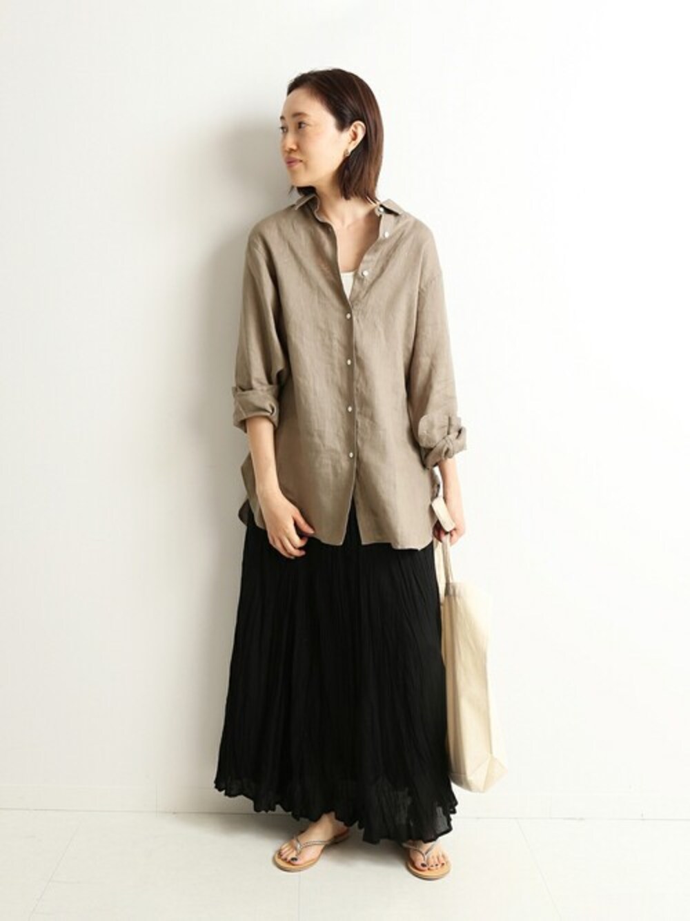 ブラック系のスカート、ホワイト系のタンクトップ、ホワイト系のトートバッグを着用したレディースの春コーディネートの1枚目の写真