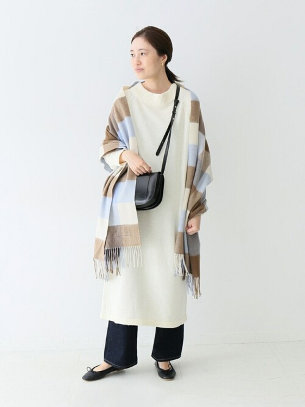 ベージュ系のワンピース、ブルー系のデニムパンツ、ブラック系のバレエシューズを着用したレディースの秋コーディネートの1枚目の写真