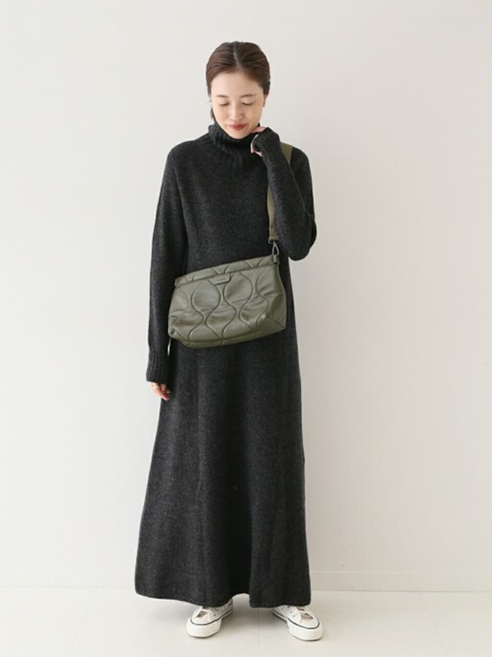 ブラック系のワンピース、グリーン系のショルダーバッグを着用したレディースの秋コーディネートの1枚目の写真