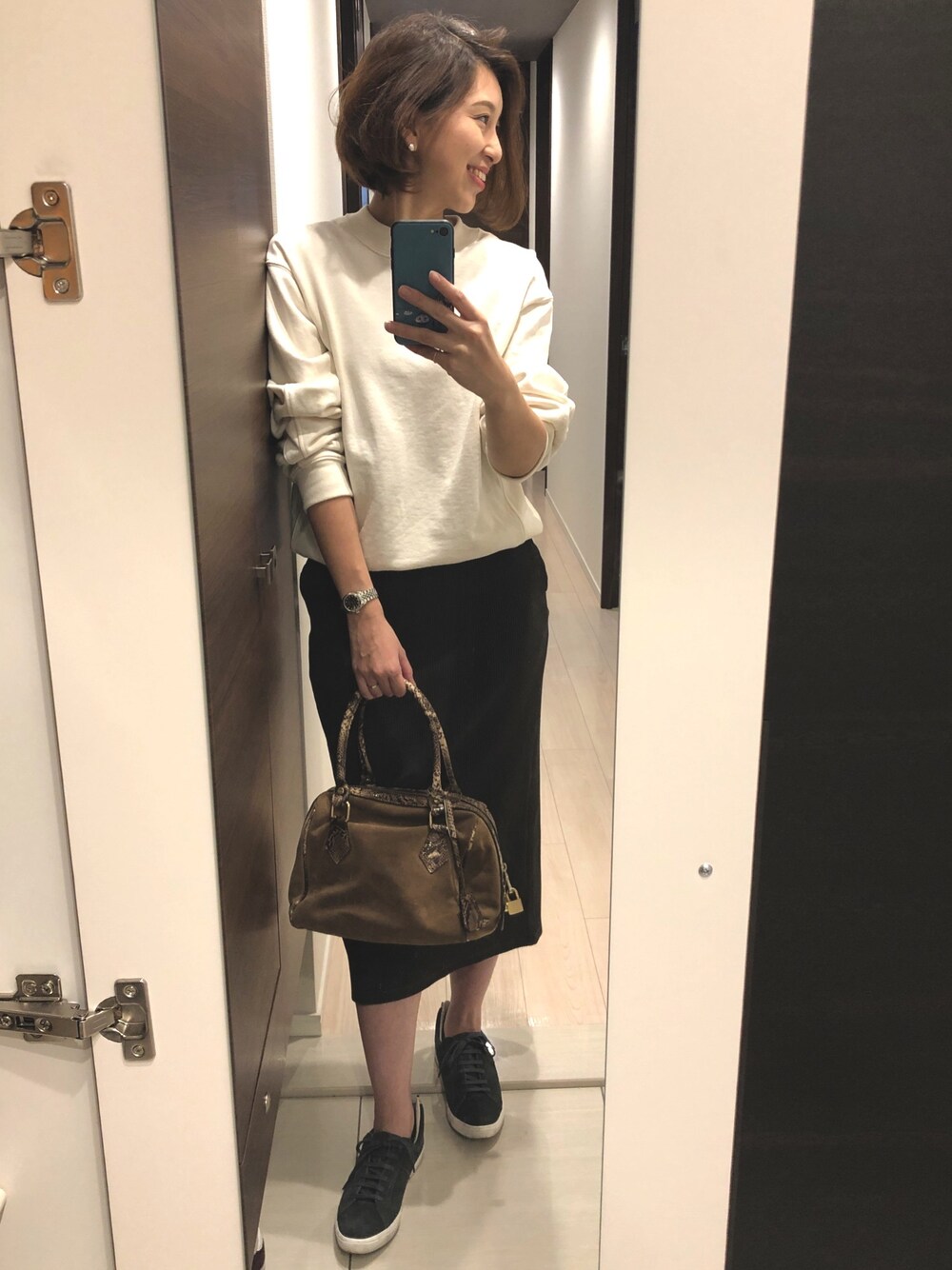 グレー系のスニーカー、グリーン系のスカート、ベージュ系のボストンバッグを着用したレディースの秋コーディネートの1枚目の写真