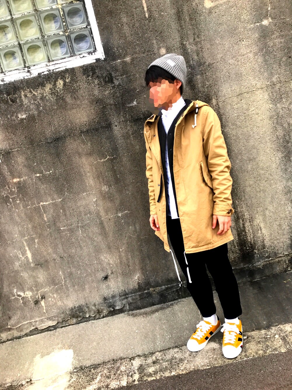 ブラウン系のモッズコート、ブラック系のパンツ、イエロー系のスニーカーを着用したメンズの冬コーディネートの1枚目の写真