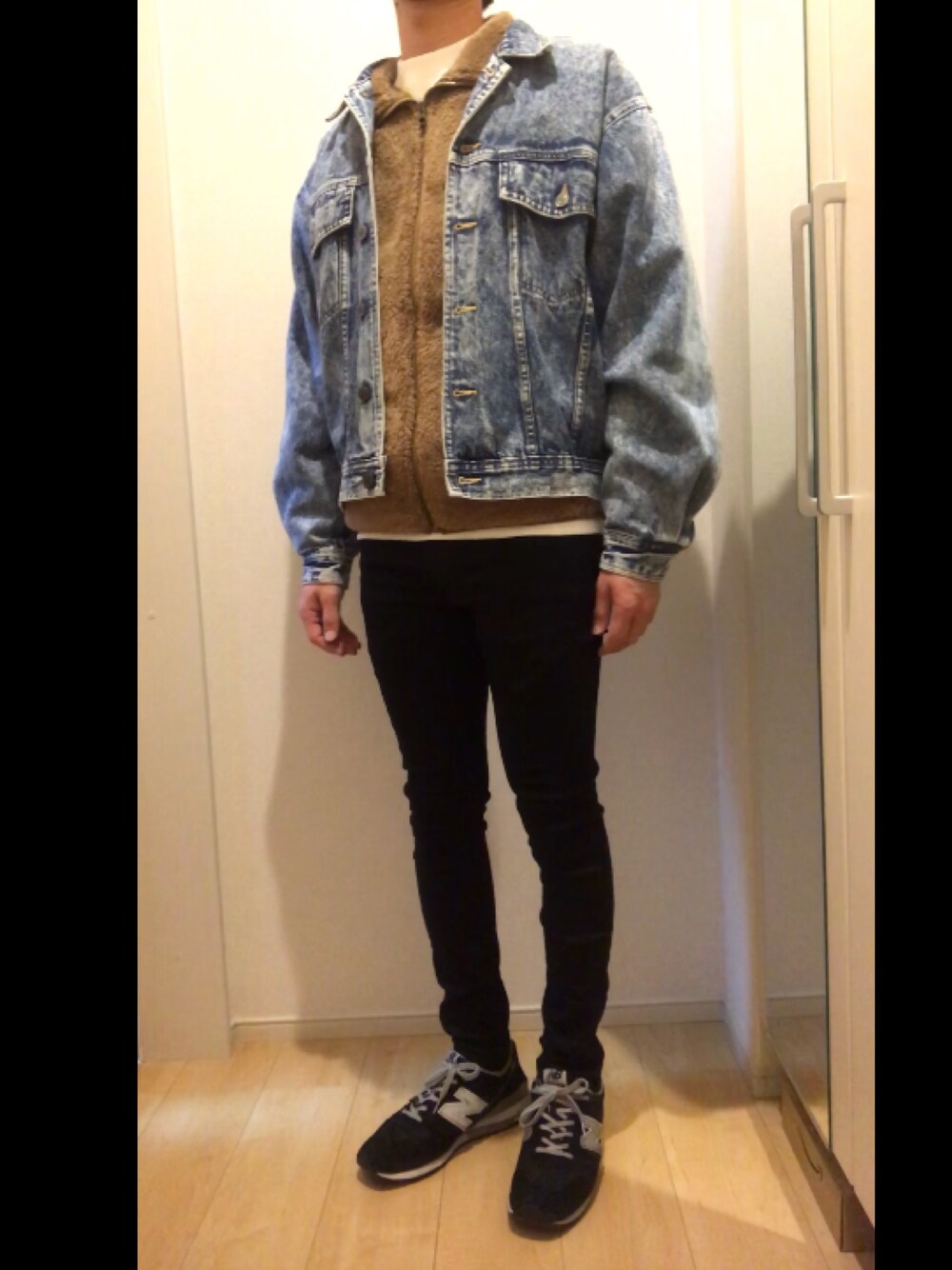 ブラック系のスニーカー、ブラック系のデニムパンツ、ホワイト系のスウェットを着用したメンズの冬コーディネートの1枚目の写真