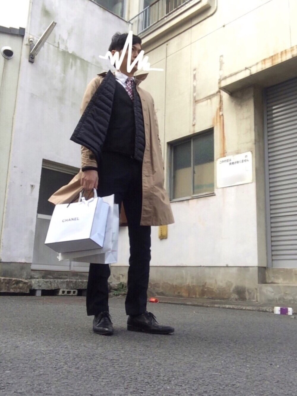 ベージュ系のステンカラーコート、ブラック系のダウンジャケット/コートを着用したメンズの春コーディネートの1枚目の写真