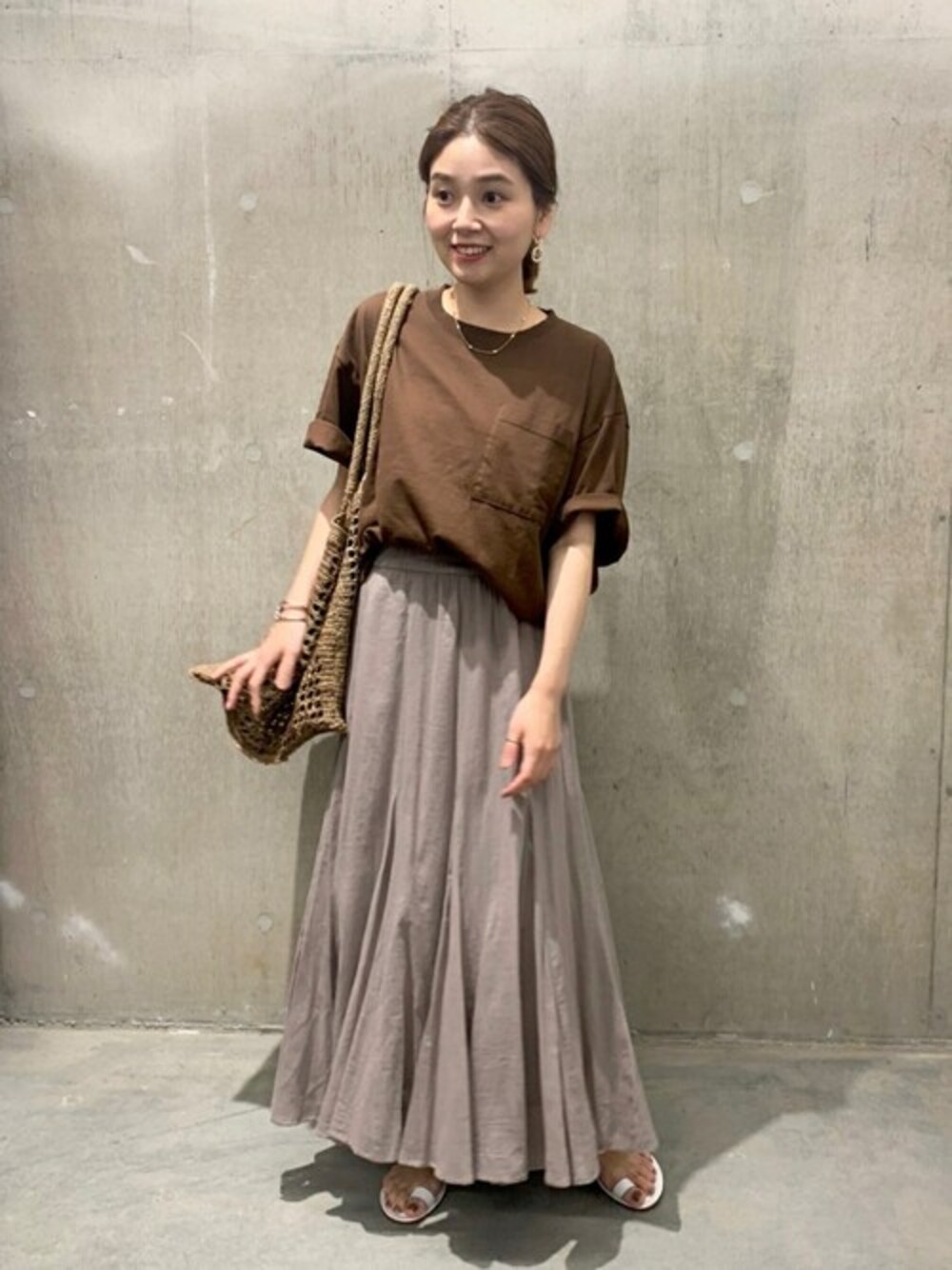 ブラウン系のTシャツ/カットソー、グレー系のスカート、ベージュ系のトートバッグを着用したレディースの夏コーディネートの1枚目の写真