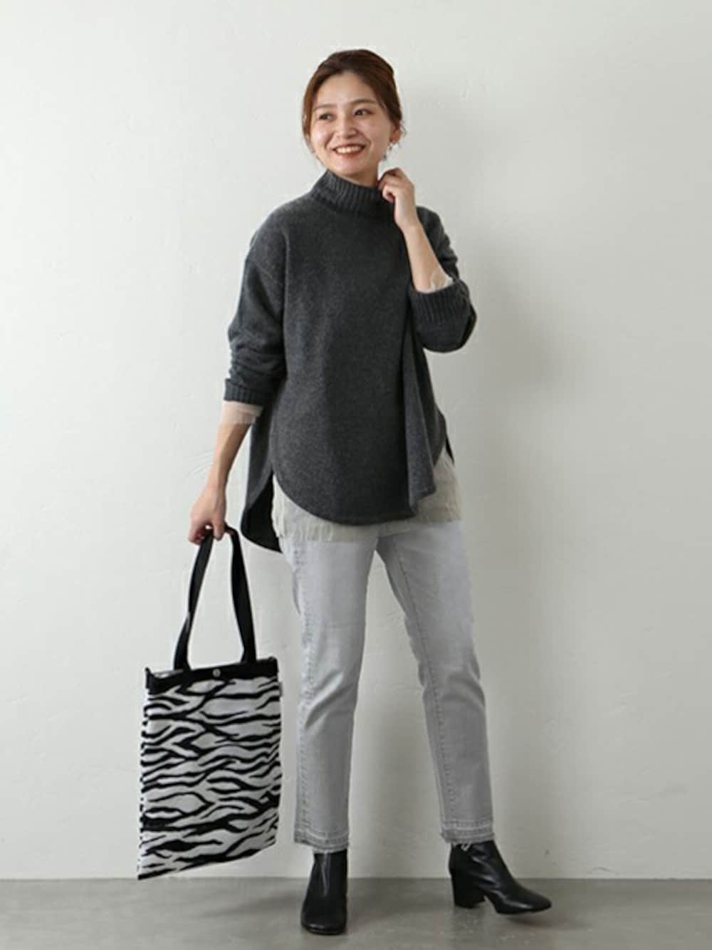 グレー系のデニムパンツ、グレー系のニット/セーター、ホワイト系のトートバッグを着用したレディースの秋コーディネートの1枚目の写真