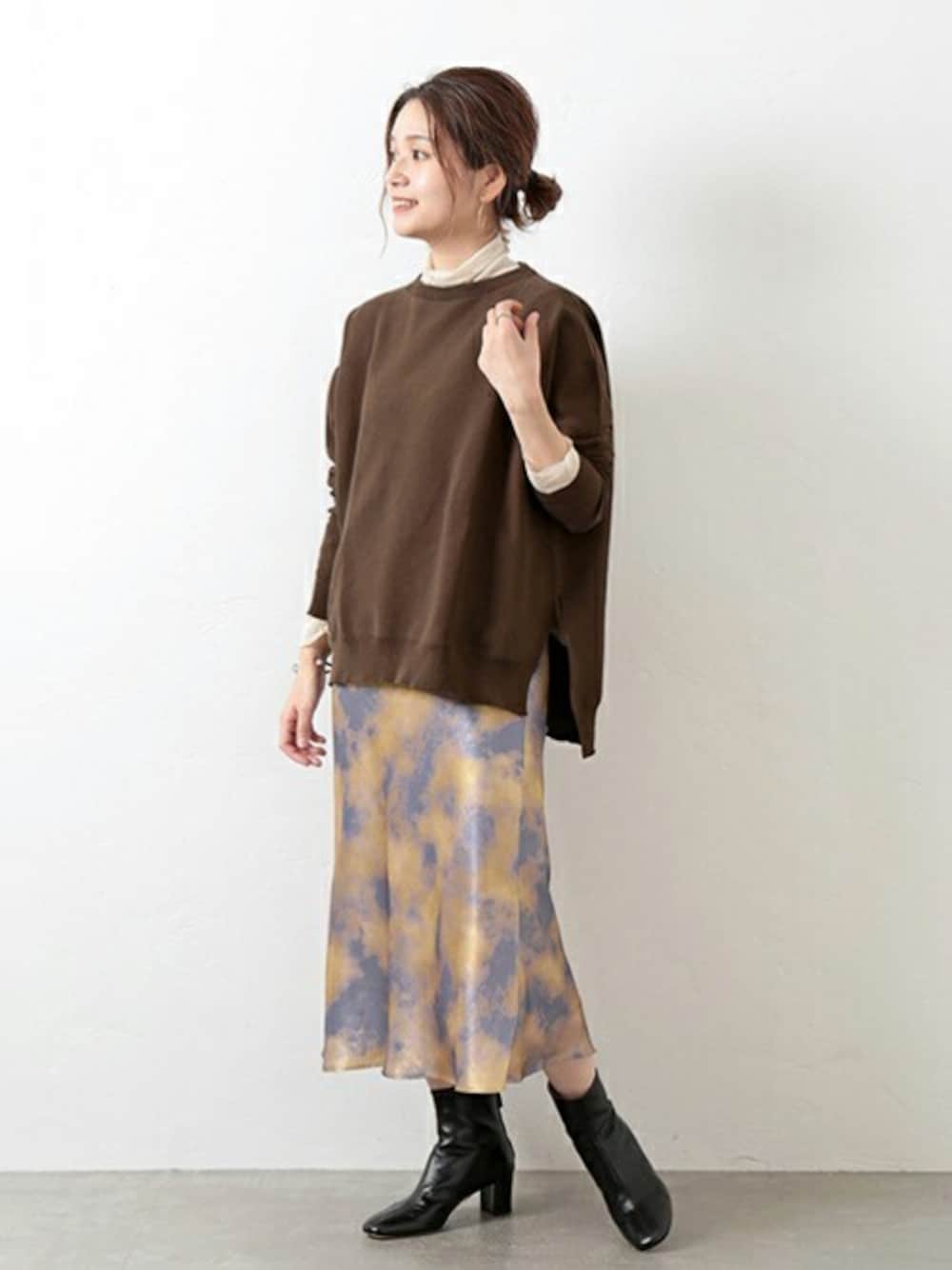 ブラウン系のニット/セーター、オレンジ系のスカート、ブラック系のブーツを着用したレディースの秋コーディネートの1枚目の写真