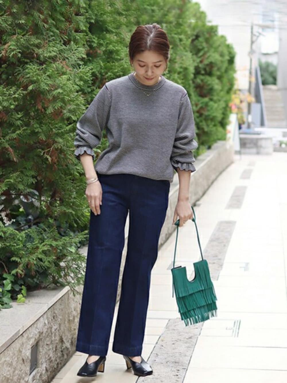 ブラック系のニット/セーター、ブルー系のデニムパンツ、グリーン系のショルダーバッグを着用したレディースの冬コーディネートの1枚目の写真