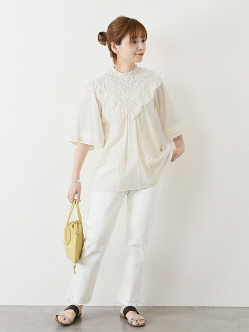 ベージュ系のデニムパンツ、イエロー系のショルダーバッグ、ベージュ系のサンダルを着用したレディースの春コーディネートの1枚目の写真