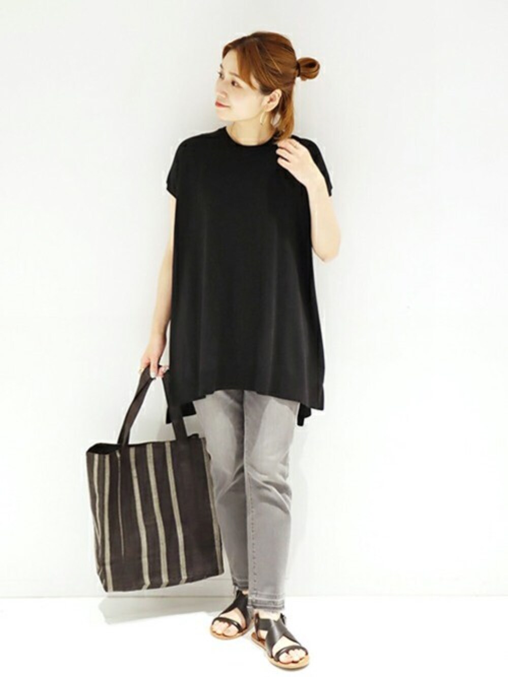 ブラック系のニット/セーター、グレー系のデニムパンツ、ベージュ系のトートバッグを着用したレディースの春コーディネートの1枚目の写真