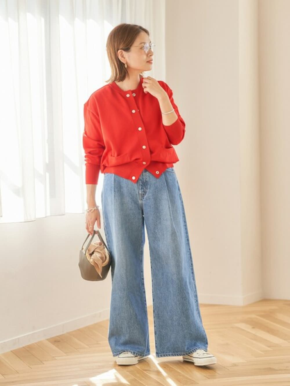 レッド系のカーディガン/ボレロ、ブルー系のデニムパンツ、ホワイト系のスニーカーを着用したレディースの冬コーディネートの1枚目の写真