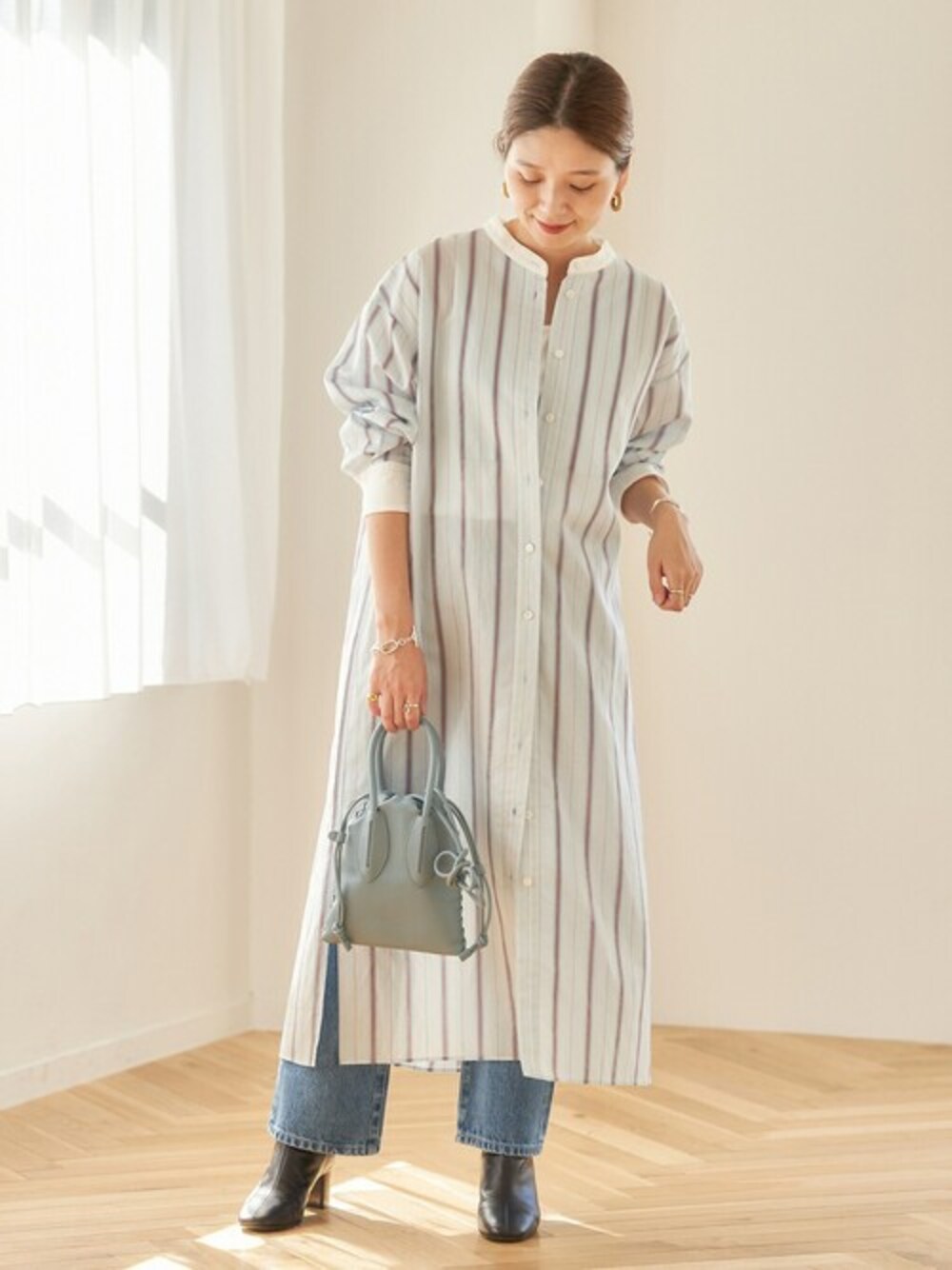 ブルー系のワンピース、ブルー系のデニムパンツ、ブルー系のショルダーバッグを着用したレディースの冬コーディネートの1枚目の写真