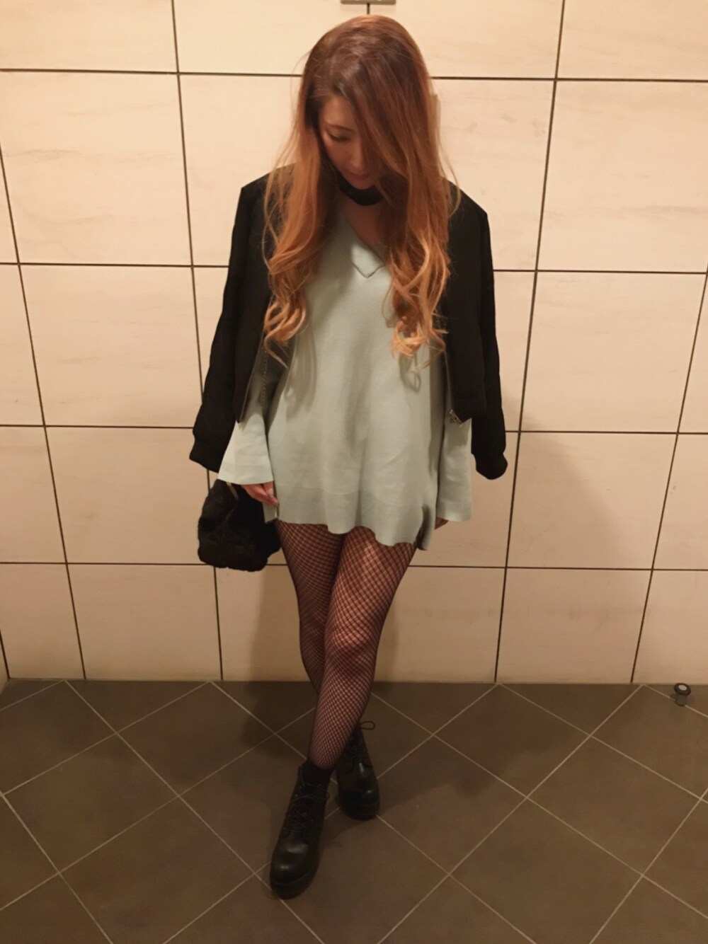 ブラック系のミリタリージャケット、グリーン系のニット/セーター、ブラック系のクラッチバッグを着用したレディースの春コーディネートの1枚目の写真