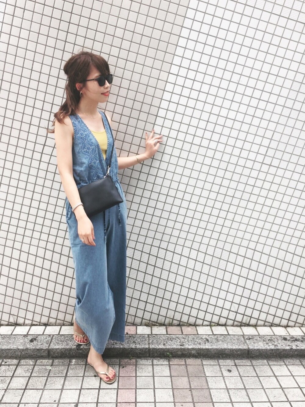 イエロー系のタンクトップ、ブルー系のサロペット/オーバーオール、ブラック系のショルダーバッグを着用したレディースの夏コーディネートの1枚目の写真