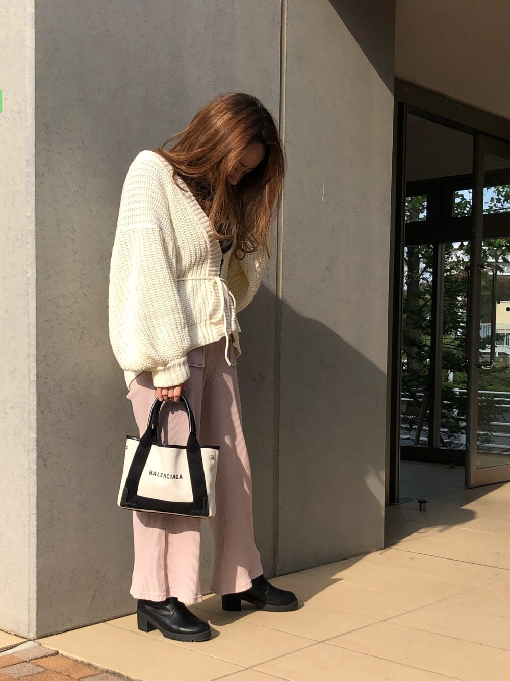 ホワイト系のカーディガン/ボレロ、ブラック系のTシャツ/カットソー、ピンク系のパンツを着用したレディースの秋コーディネートの1枚目の写真