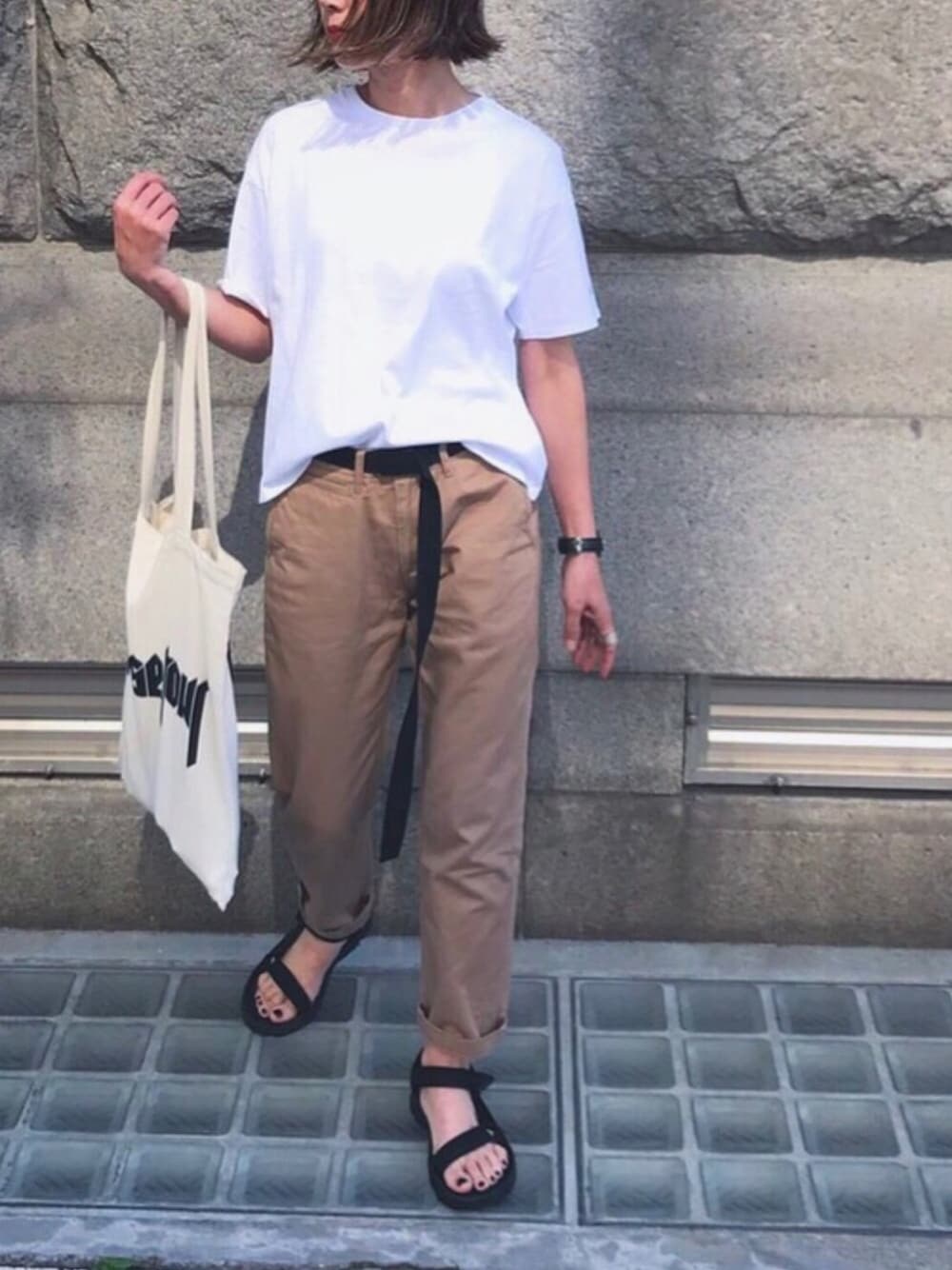 ホワイト系のTシャツ/カットソー、ブラウン系のトートバッグ、ブラック系のサンダルを着用したレディースの春コーディネートの1枚目の写真