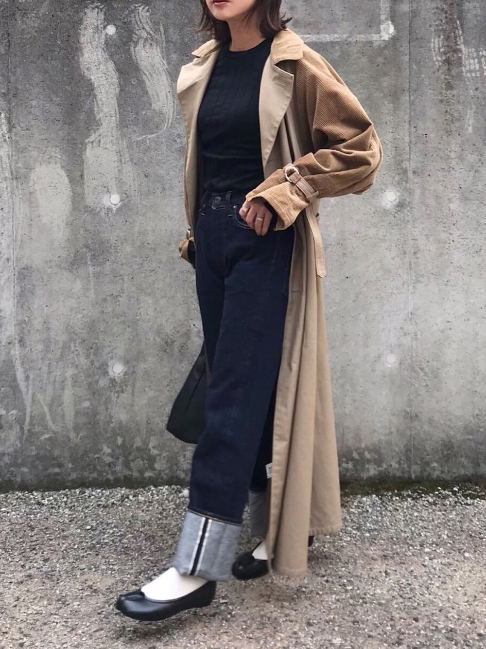 ブラック系のTシャツ/カットソー、ベージュ系のトレンチコート、ブルー系のデニムパンツを着用したレディースの冬コーディネートの1枚目の写真