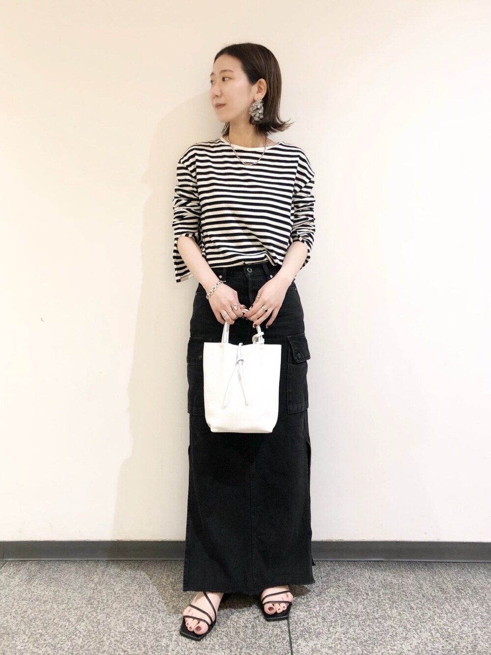 ブラック系のTシャツ/カットソー、ブラック系のデニムスカート、ホワイト系のバッグを着用したレディースの春コーディネートの1枚目の写真