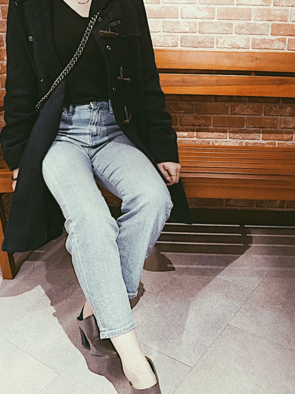 ホワイト系のダッフルコート、ブラック系のニット/セーター、ブルー系のデニムパンツを着用したレディースの冬コーディネートの1枚目の写真