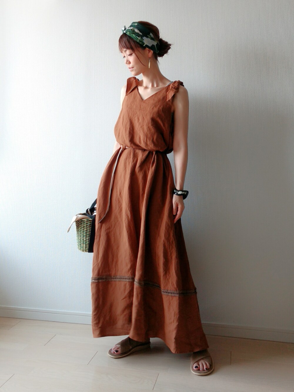 ブラウン系のワンピース、グリーン系のかごバッグ、ベージュ系のサンダルを着用したレディースの夏コーディネートの1枚目の写真