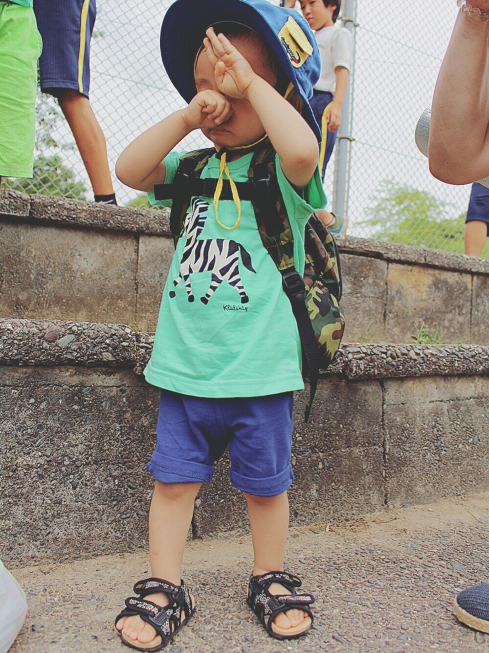 グリーン系のTシャツ/カットソー、ブルー系のパンツ、ブラック系のサンダルを着用したキッズの夏コーディネートの1枚目の写真