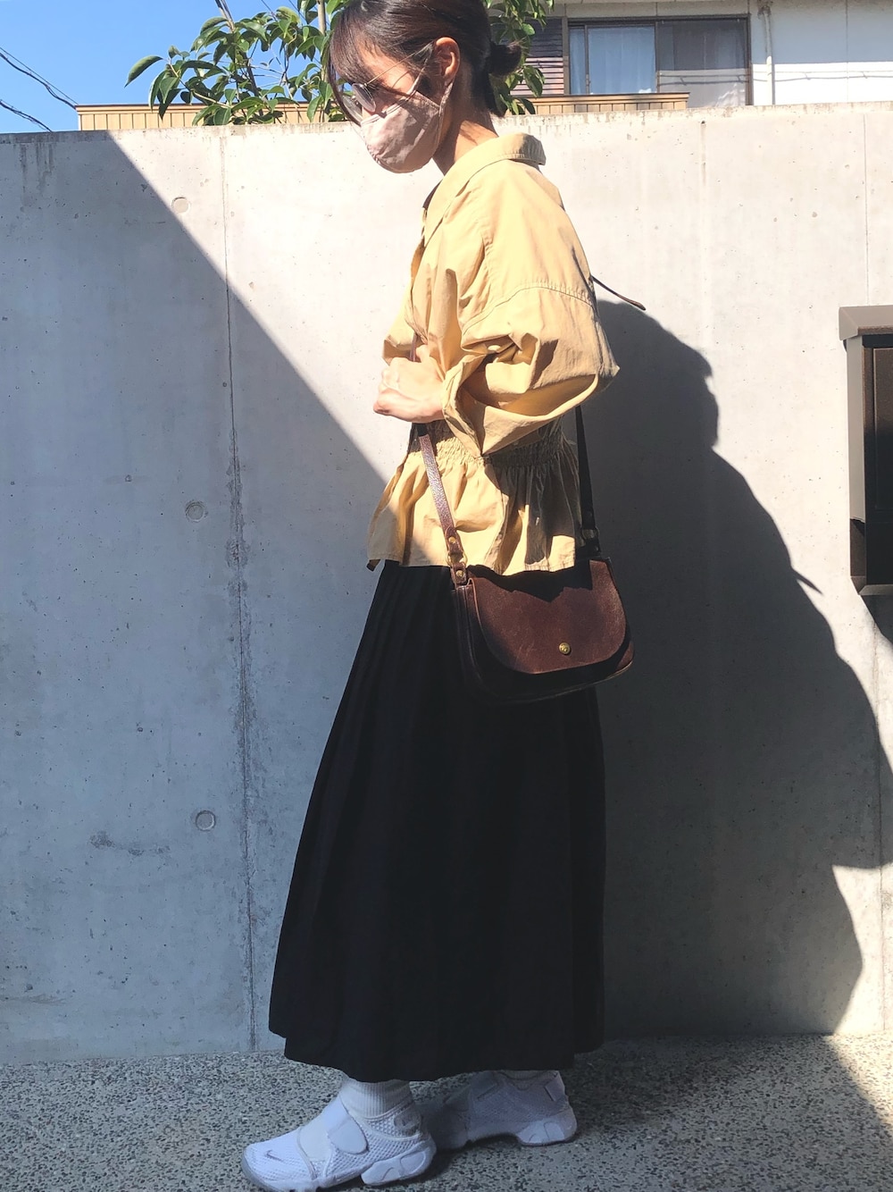 ブラウン系のショルダーバッグ、ベージュ系のシャツ/ブラウス、ホワイト系のスニーカーを着用したレディースの秋コーディネートの1枚目の写真