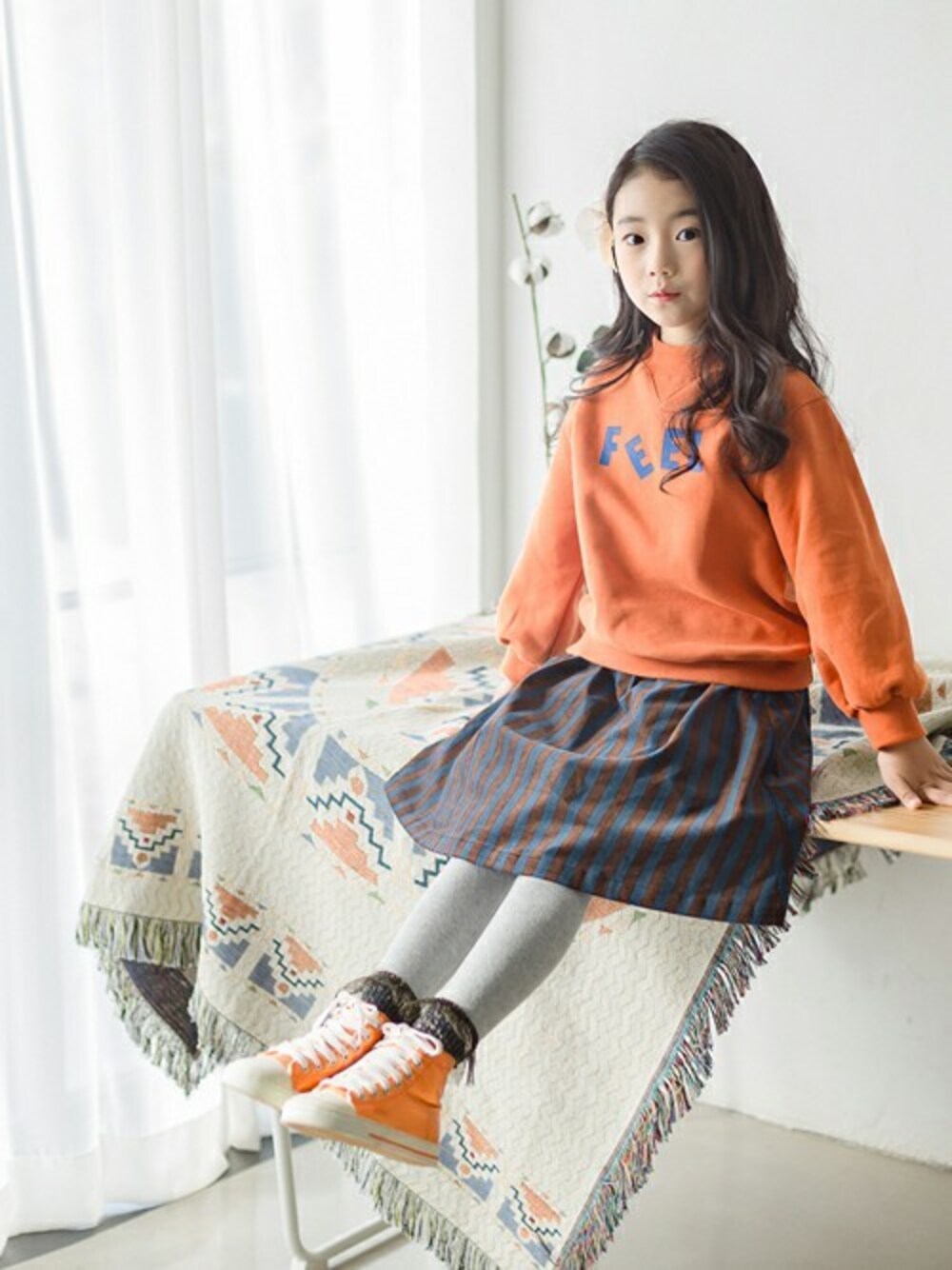 ブルー系のスカート、オレンジ系のスウェットを着用したキッズの冬コーディネートの1枚目の写真
