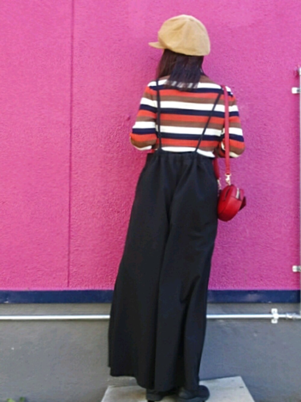 ブラック系のサロペット/オーバーオール、レッド系のショルダーバッグ、オレンジ系のニット/セーターを着用したレディースの秋コーディネートの1枚目の写真