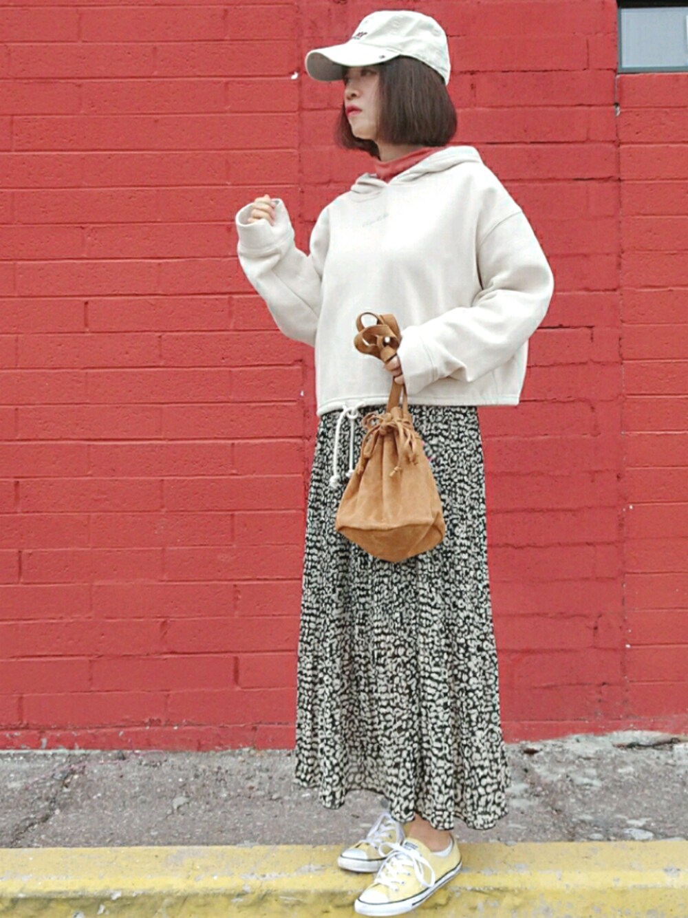 ホワイト系のパーカー、ブラック系のスカート、オレンジ系のTシャツ/カットソーを着用したレディースの冬コーディネートの1枚目の写真