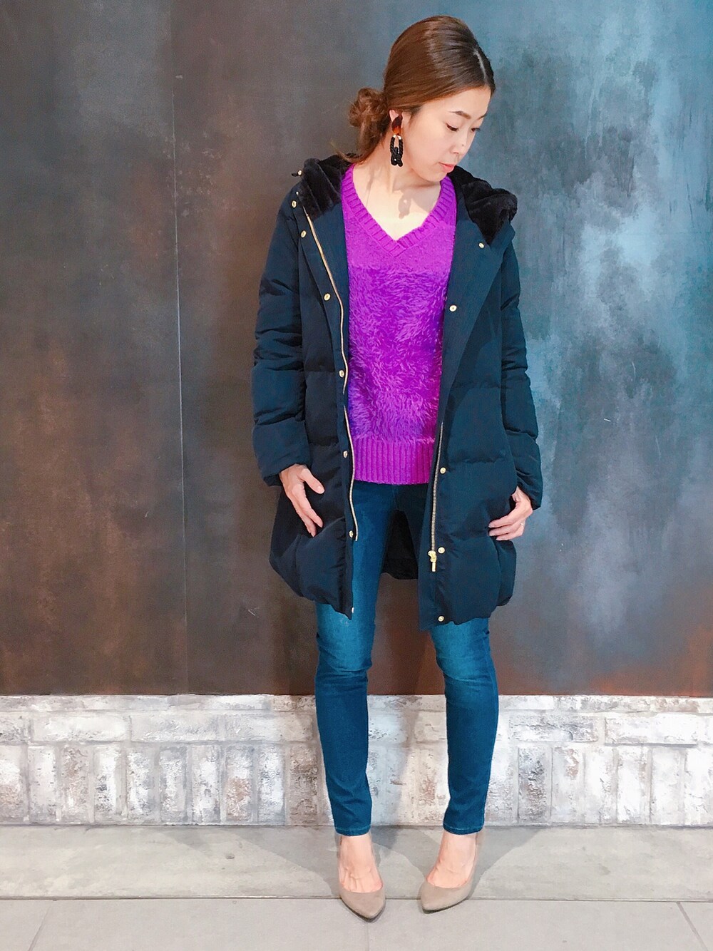 ブルー系のダウンジャケット/コート、パープル系のニット/セーター、ブルー系のデニムパンツを着用したレディースの冬コーディネートの1枚目の写真
