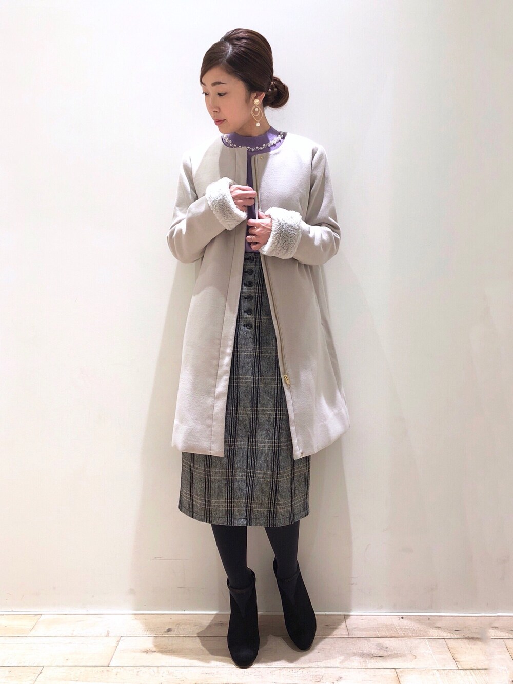 パープル系のニット/セーター、ベージュ系のダウンジャケット/コート、ブラック系のスカートを着用したレディースの冬コーディネートの1枚目の写真