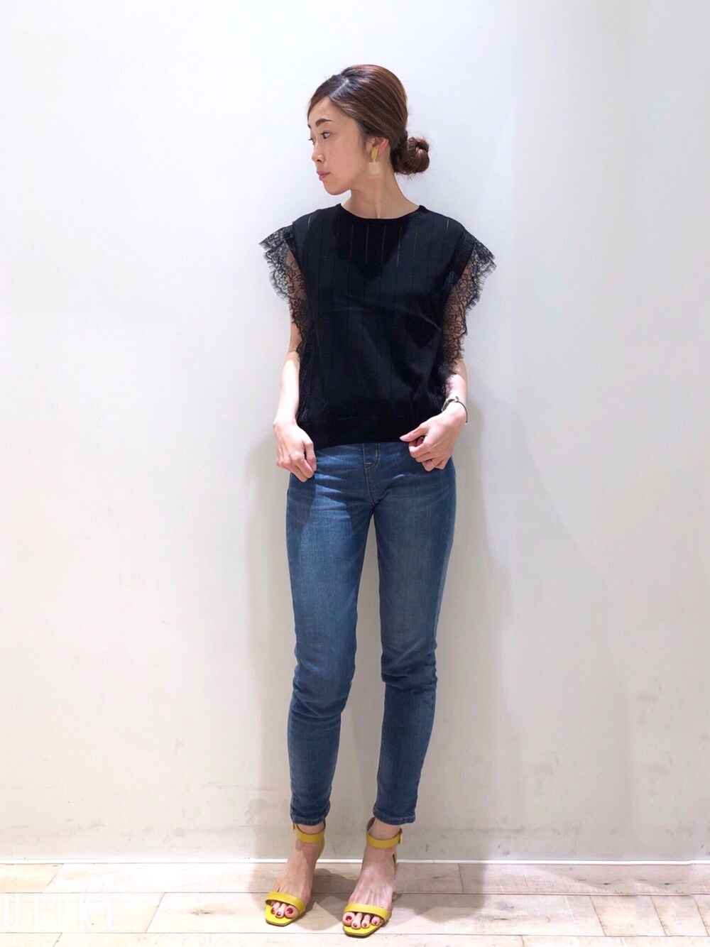 ブラック系のニット/セーター、ブルー系のその他パンツ、イエロー系のサンダルを着用したレディースの春コーディネートの1枚目の写真