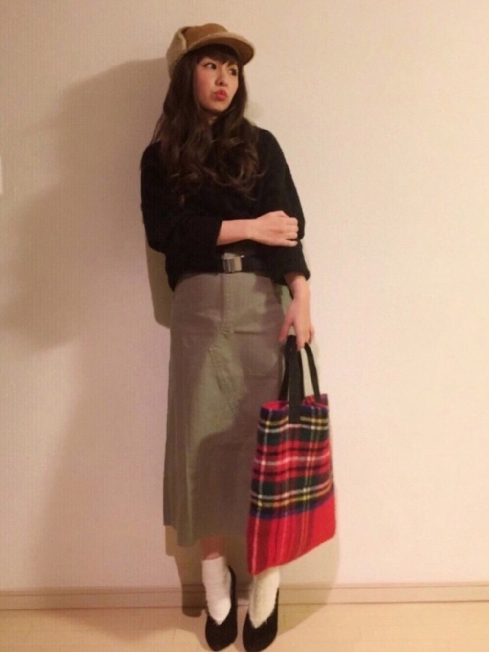 ブラック系のニット/セーター、レッド系のトートバッグ、グリーン系のスカートを着用したレディースの冬コーディネートの1枚目の写真