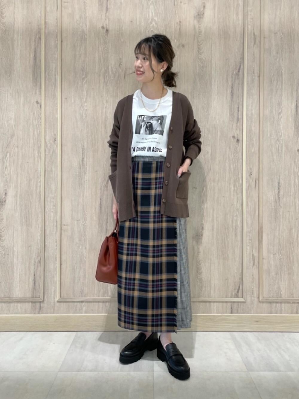 ホワイト系のTシャツ/カットソー、ブラック系のスカート、ブラウン系のカーディガン/ボレロを着用したレディースの秋コーディネートの1枚目の写真
