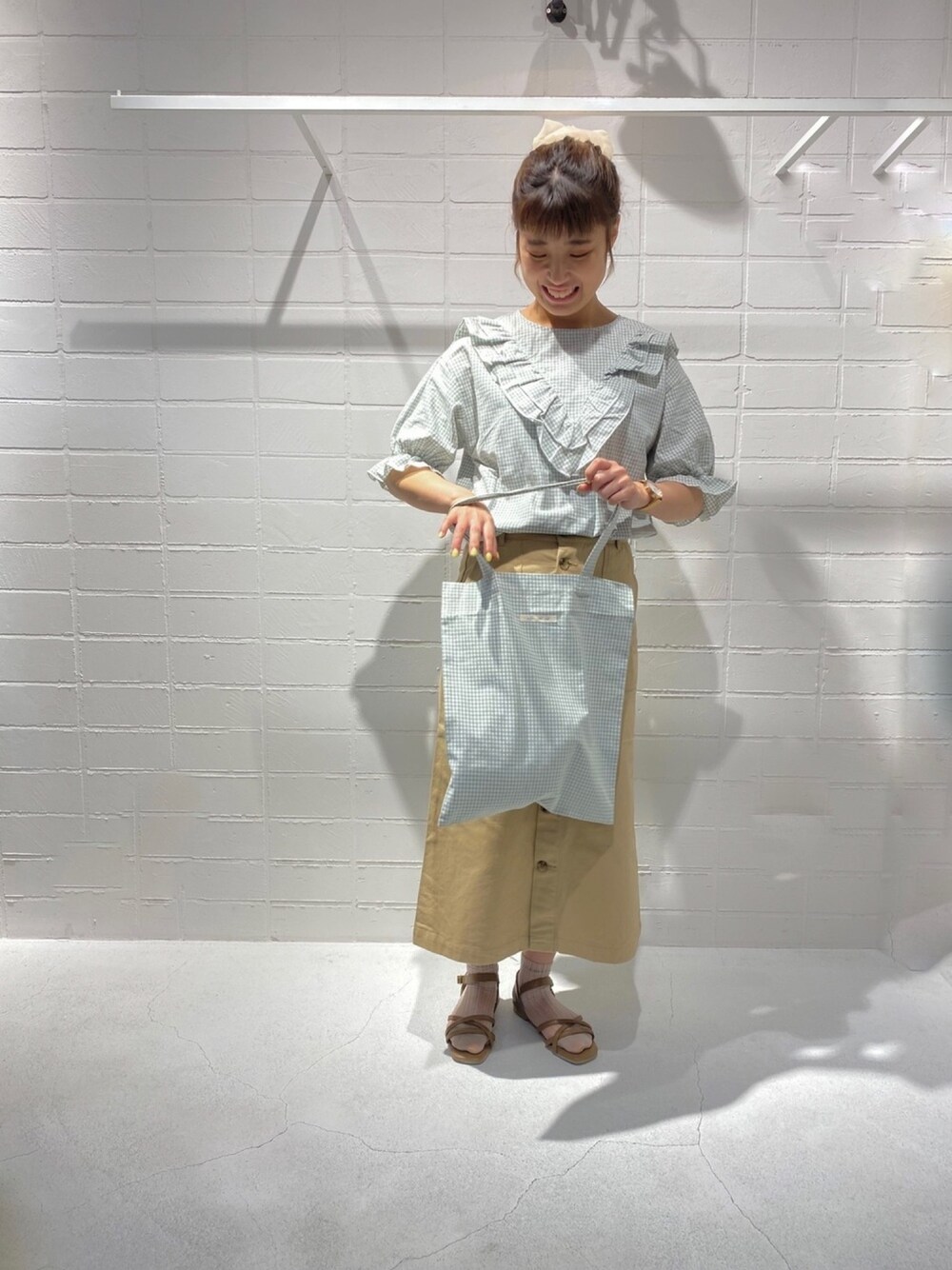 グリーン系のシャツ/ブラウス、ベージュ系のスカート、ベージュ系のサンダルを着用したレディースの春コーディネートの1枚目の写真