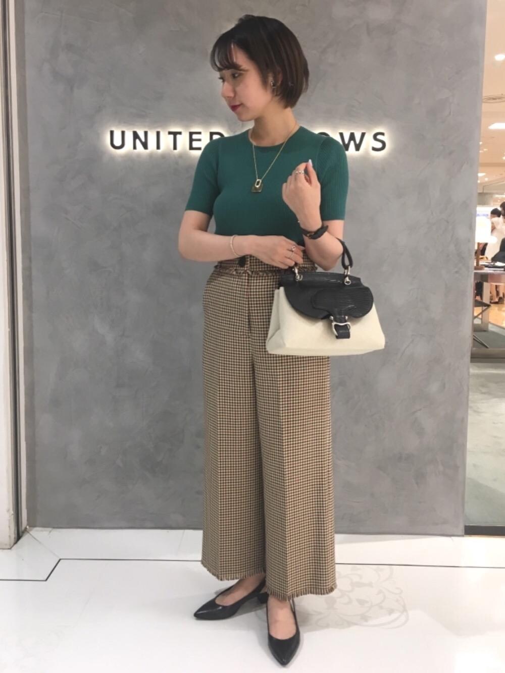 ブラック系のパンプス、グリーン系のニット/セーター、イエロー系のネックレスを着用したレディースの夏コーディネートの1枚目の写真