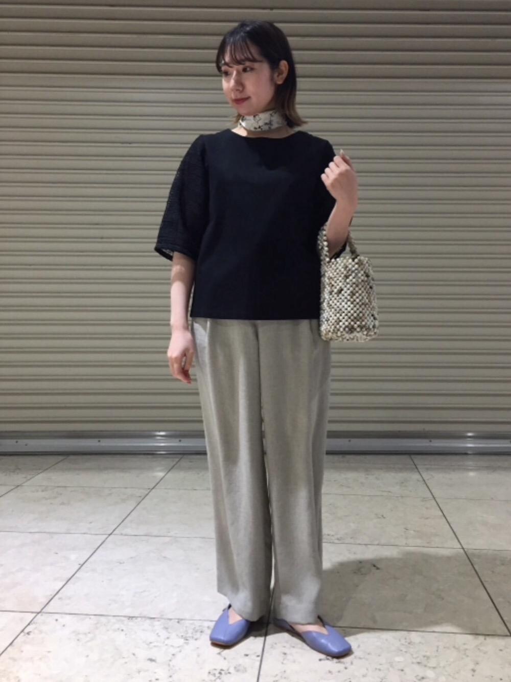 ホワイト系のハンドバッグ、ベージュ系のその他パンツ、ブラック系のTシャツ/カットソーを着用したレディースの春コーディネートの1枚目の写真