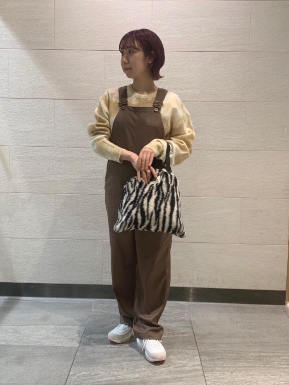 ベージュ系のスニーカー、ベージュ系のニット/セーター、ブラウン系のサロペット/オーバーオールを着用したレディースの秋コーディネートの1枚目の写真